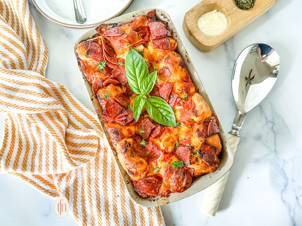 Baked pizza pull apart bread garnished with fresh basil, served in a loaf pan.