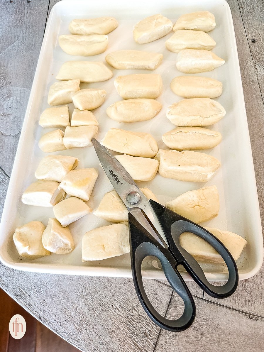 Cutting unbaked Bridgford Parkerhouse style rolls into pieces for pull apart bread recipe.