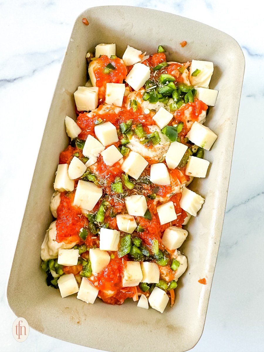 One unbaked layer of pizza casserole in a baking dish.