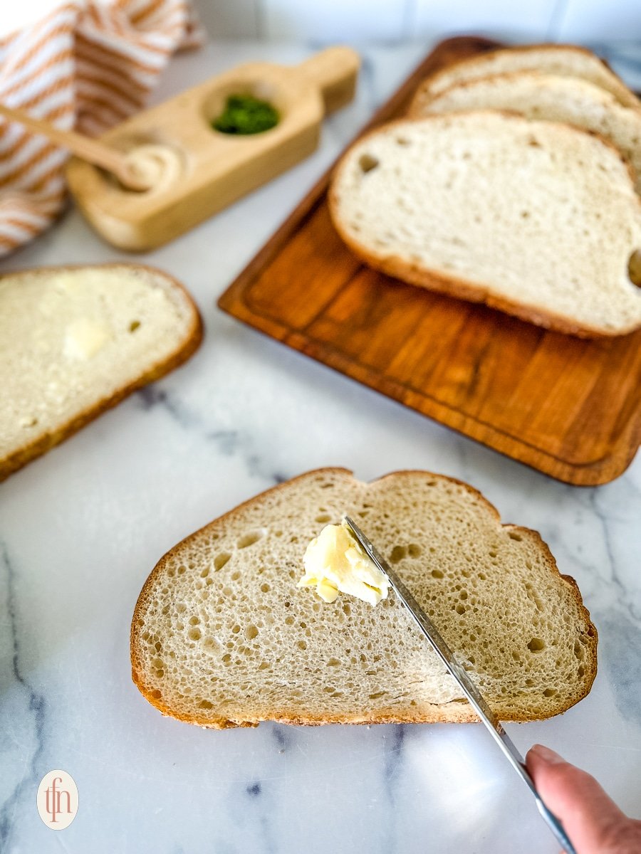 Spreading butter on a slice of garlic bread.