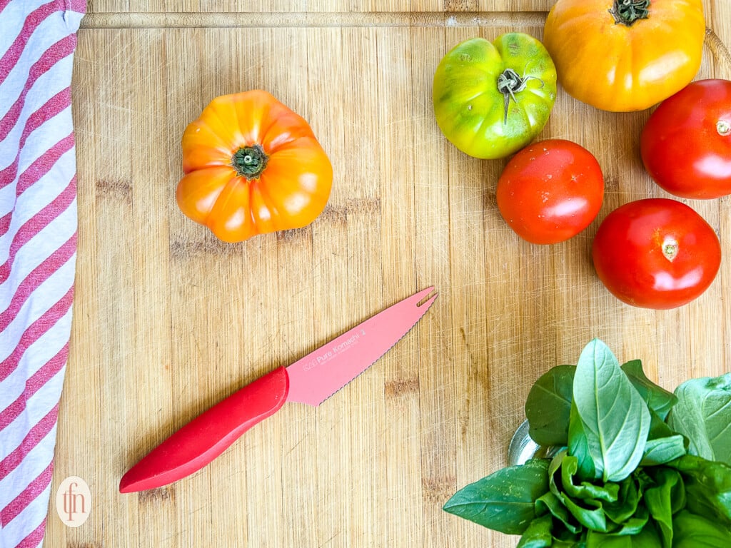 Ingredients for a burrata caprese salad on a cutting board.