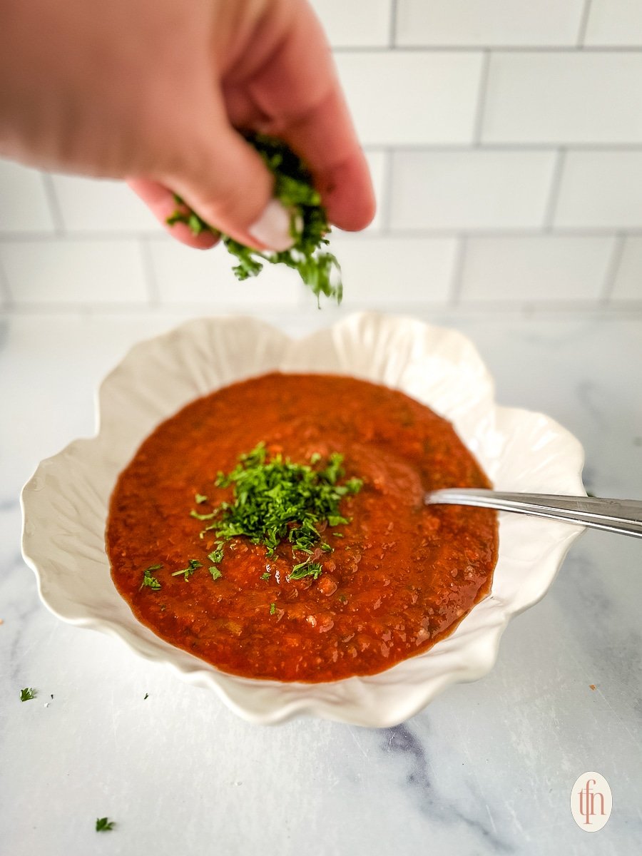 Salsa in a white bowl topped with fresh herbs.