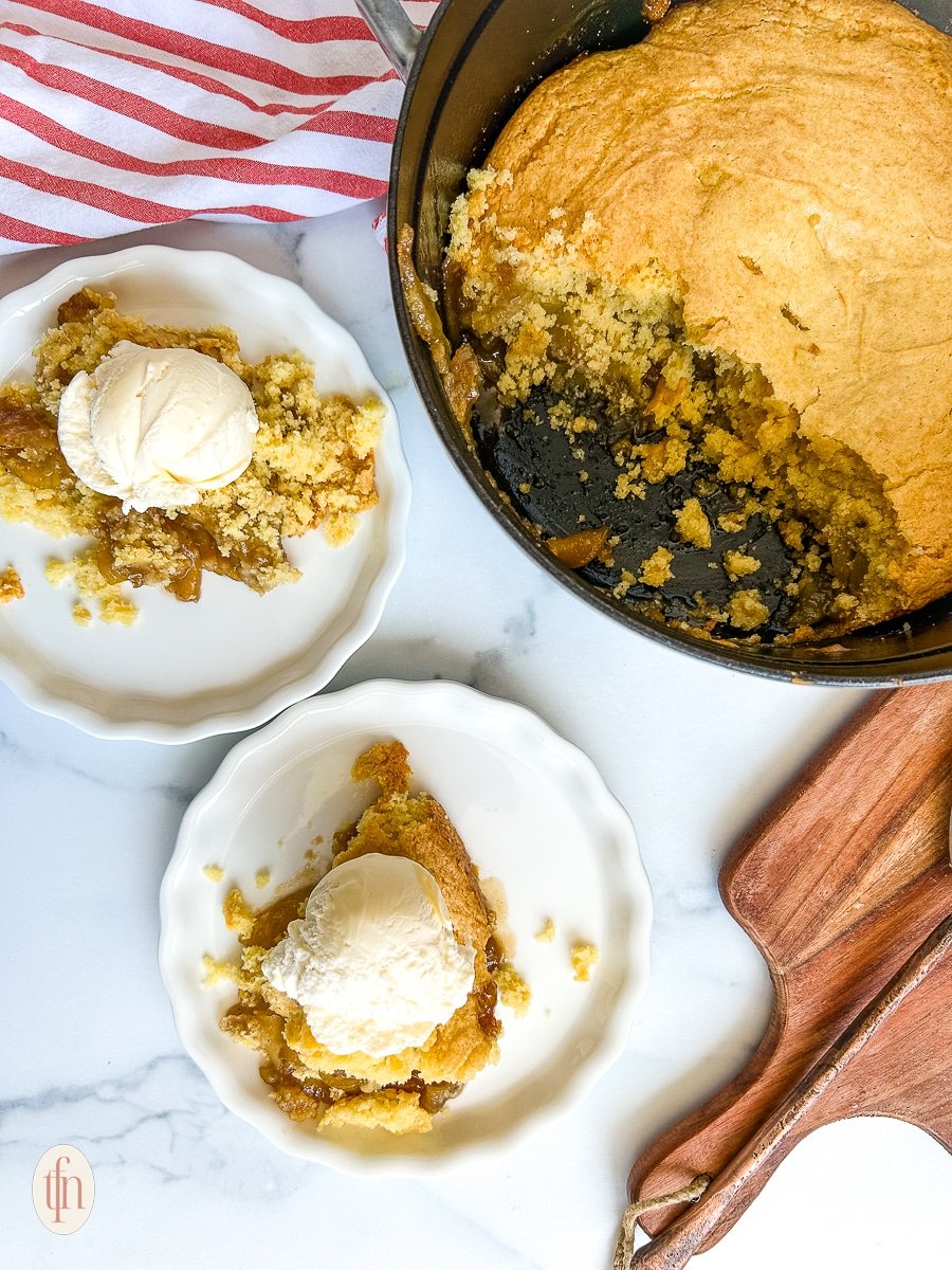 Two plates of apple cobbler with ice cream on top.