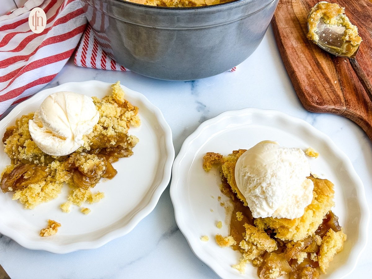 Two plates of apple cobbler with ice cream on top.