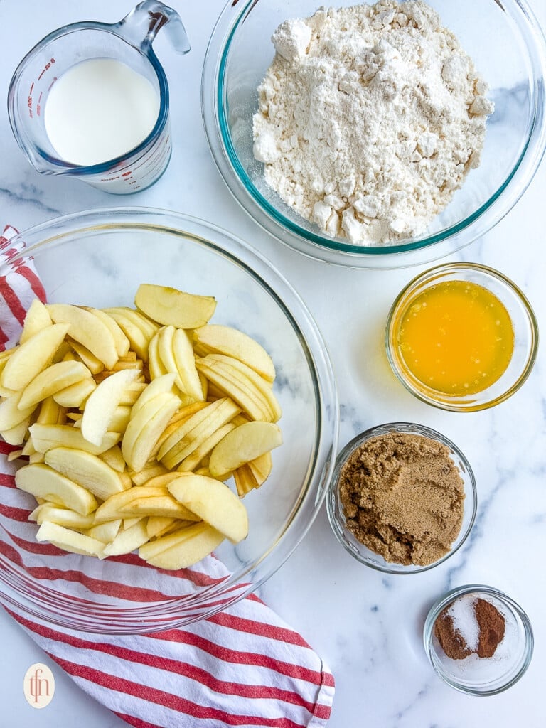 Ingredients to make apple cobbler with cake mix in small glass bowls.