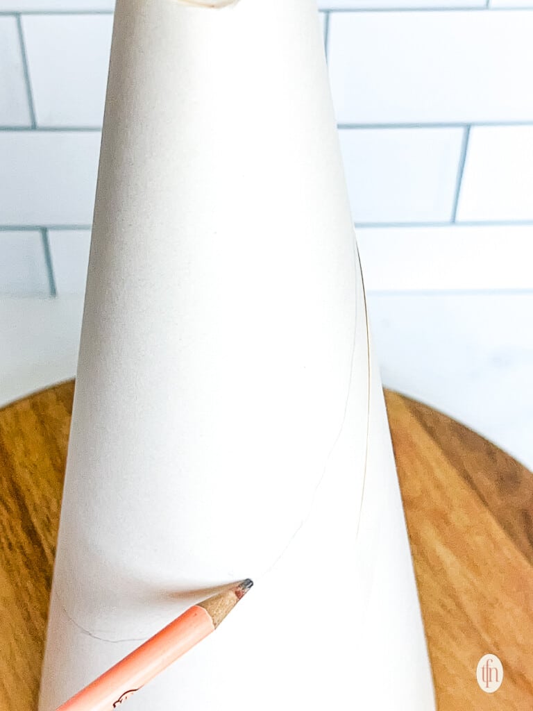 Drawing a line on a styrofoam cone with a pencil. 