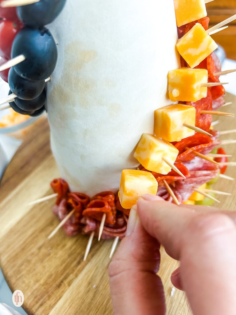 Placing a cube of cheese on a cone with a toothpick.