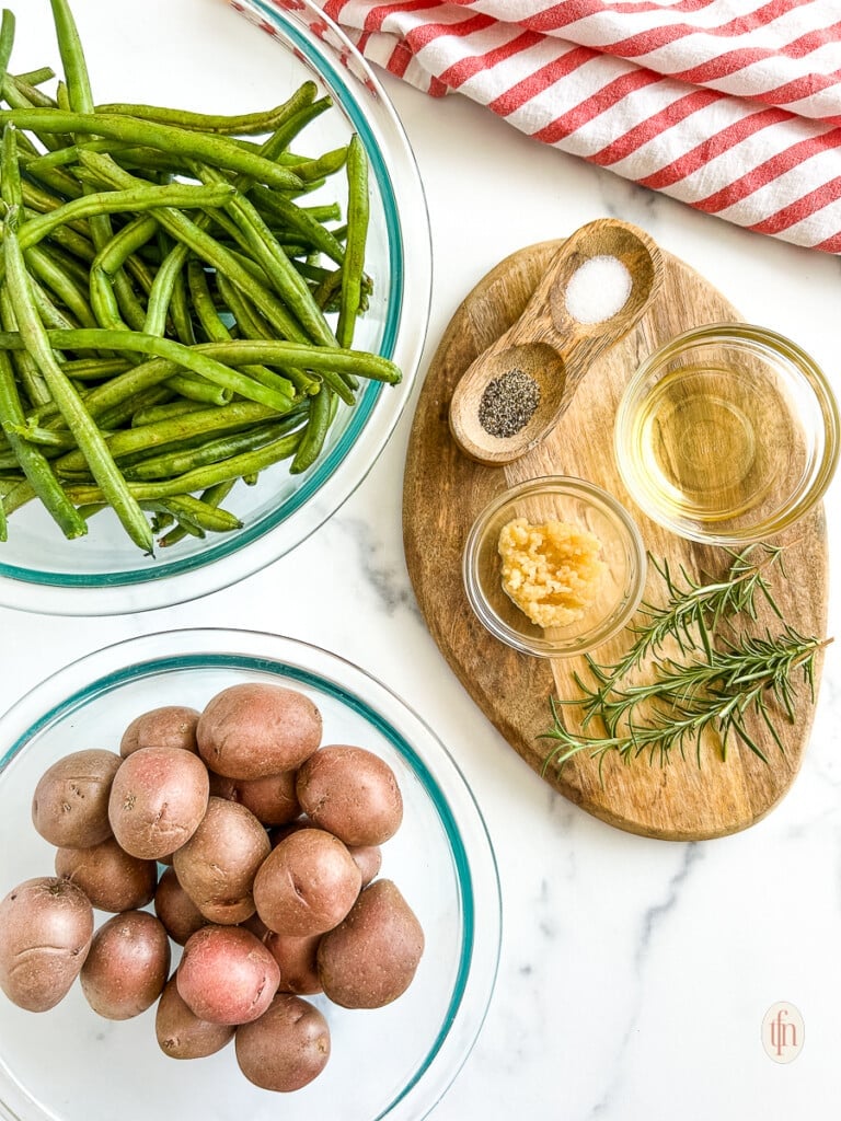 Ingredients for roasted green beans and potatoes on a white background.
