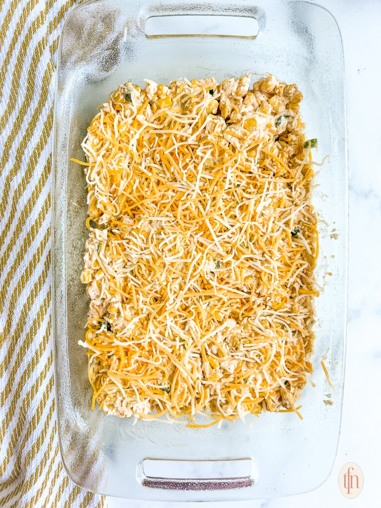 Dish covered with shredded cheese on a white background.