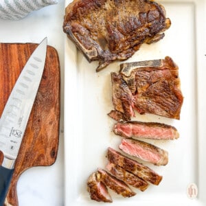 grilled strip steak cooked to medium rare, partially cut in slices on a cutting board