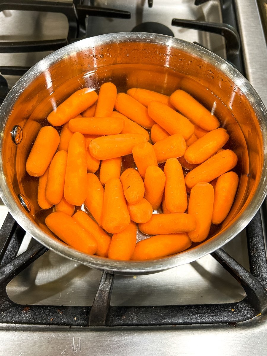 Baby carrots heating up in a pot of water.