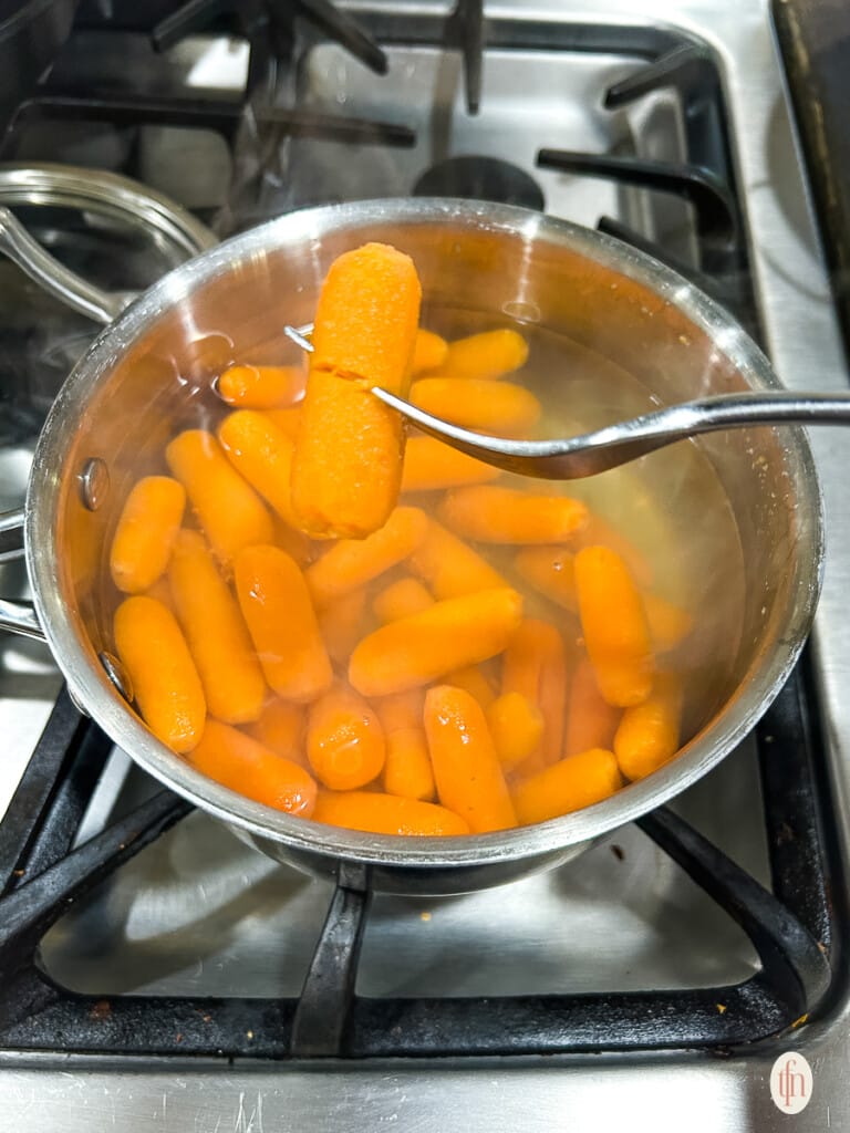 Carrots cooking in a pot on the stove.