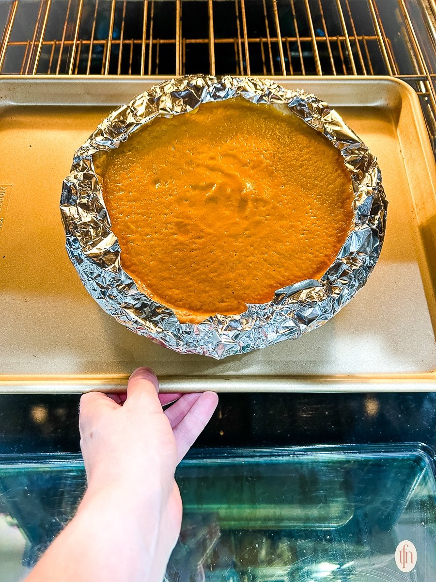 Unbaked savory pie in oven. Aluminum foil wrapped around crust.