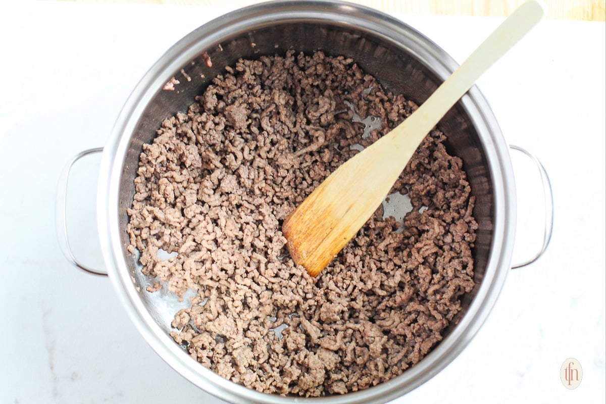 Browning ground beef in a pot on stove top.