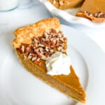 Slice of pumpkin custard pie topped with whipped cream.