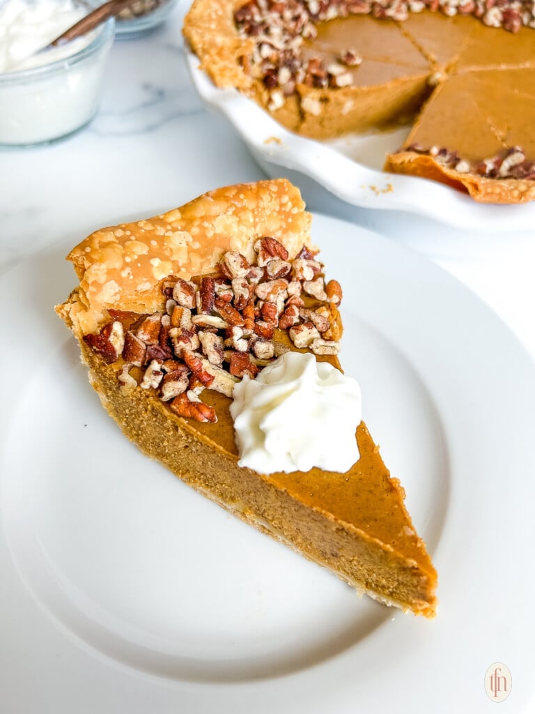 Slice of pumpkin custard pie topped with whipped cream.