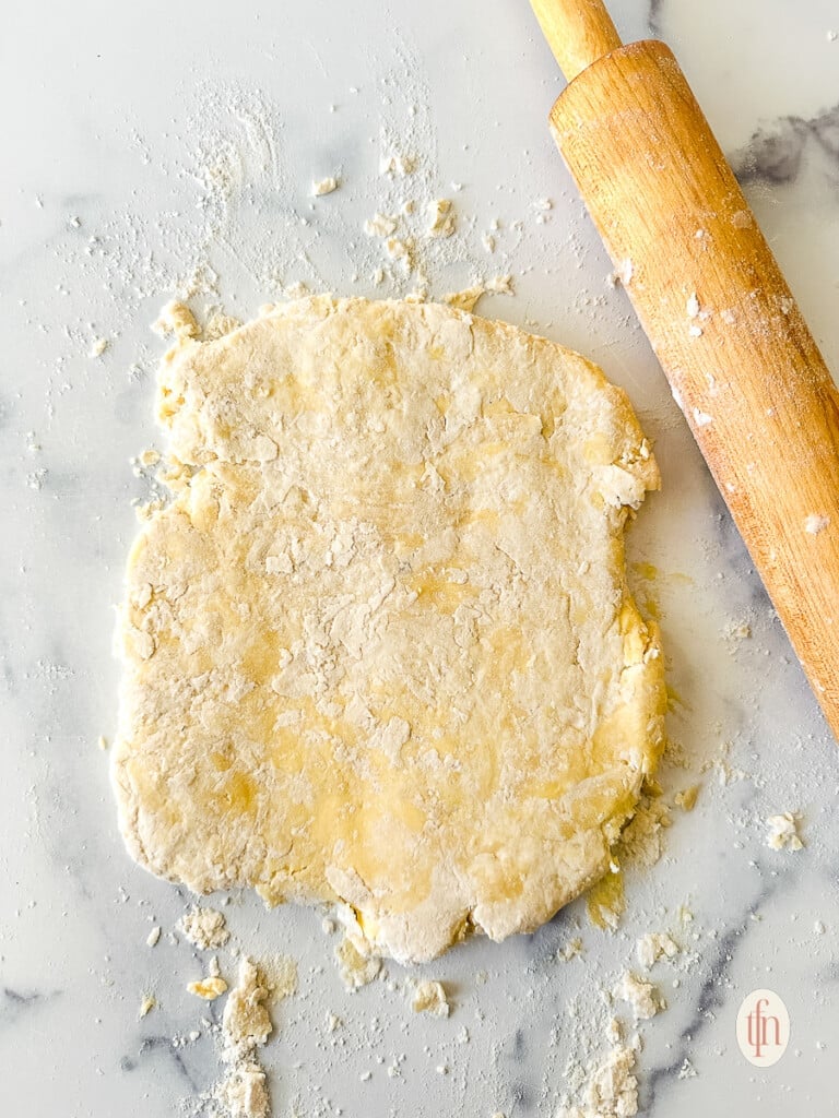 Rolled dough next to a rolling pin.