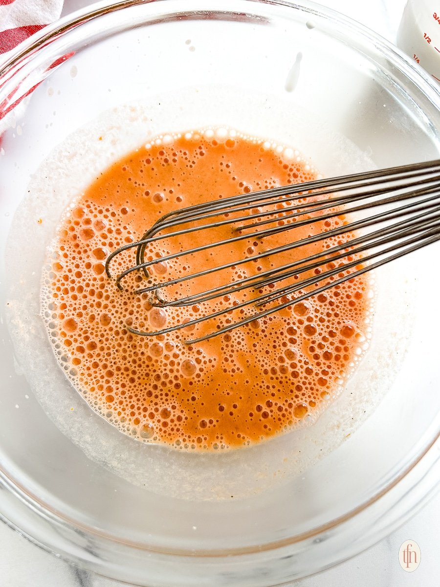 Whisking soup in a glass bowl.