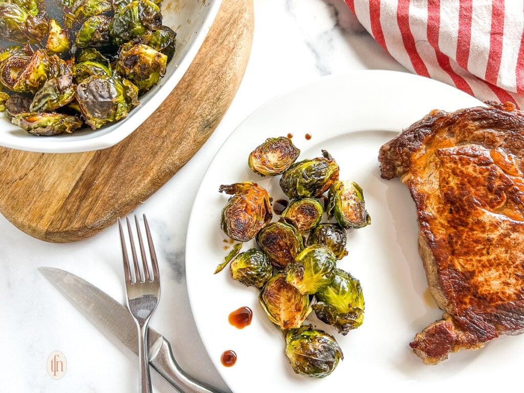 Horizontal image of maple brussel sprouts on a white plate. 