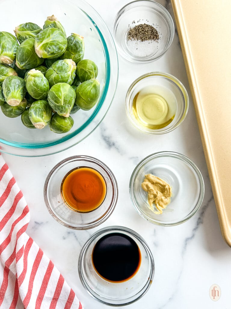 Ingredients for candied balsamic brussel sprouts in small glass bowls. 