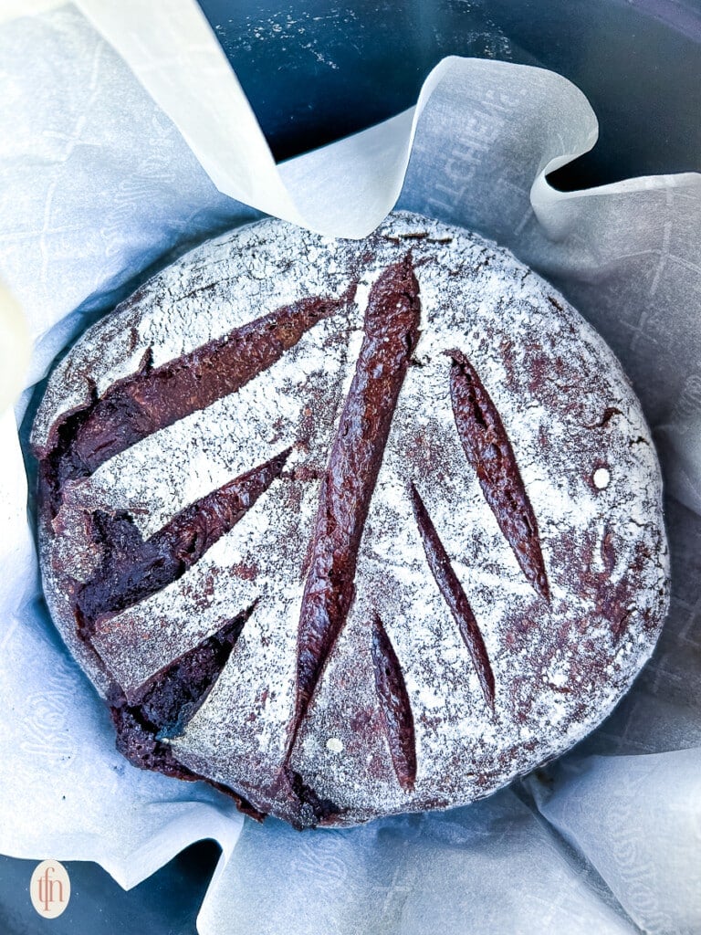 Loaf of chocolate sourdough bread in a pot with a white napkin.