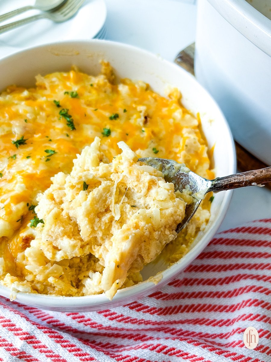 Large spoon grabbing a scoop of crockpot funeral potatoes.