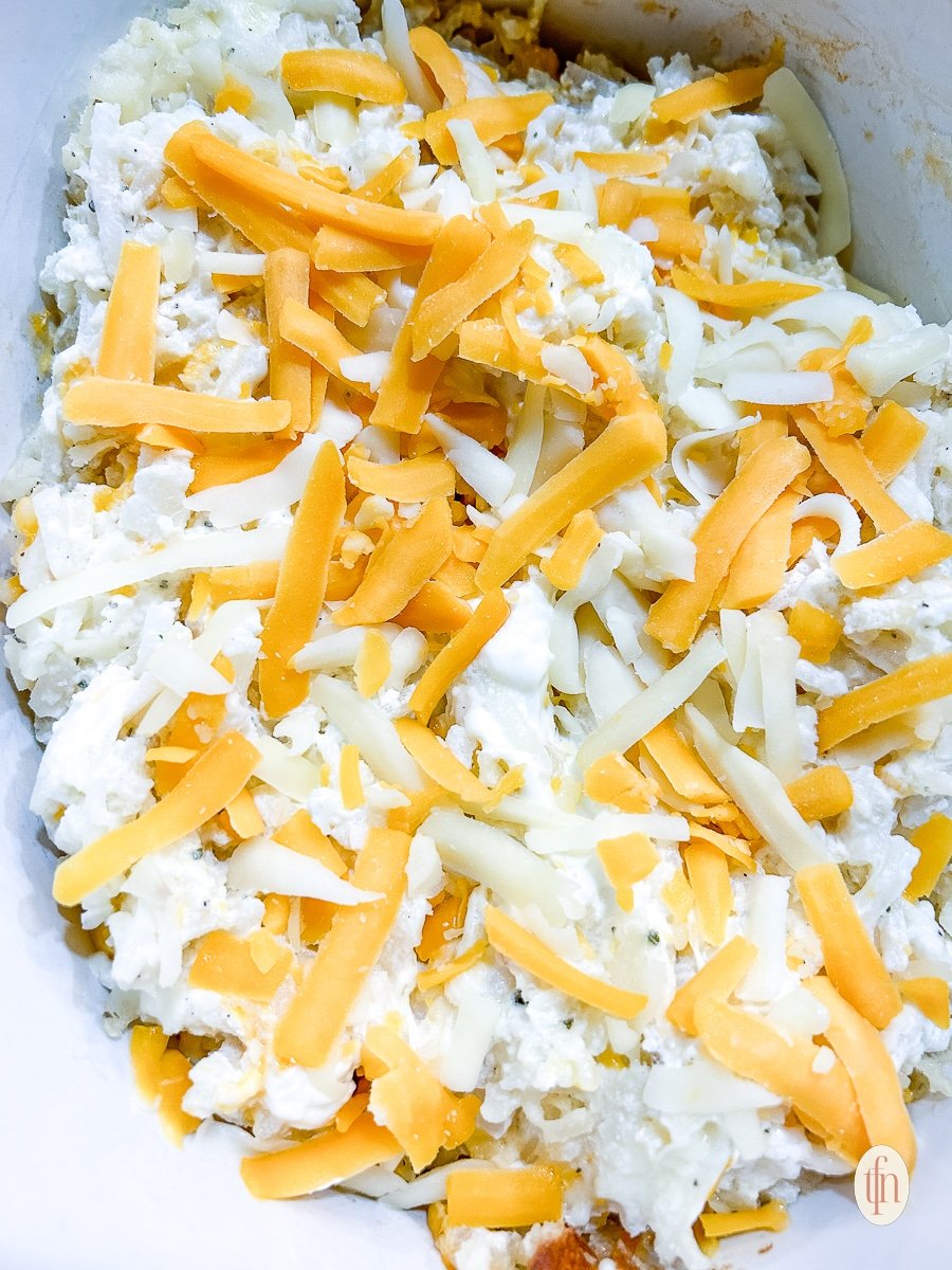 Shredded potatoes mixed with dairy products, ready to be baked into crock pot cheesy hashbrown casserole.