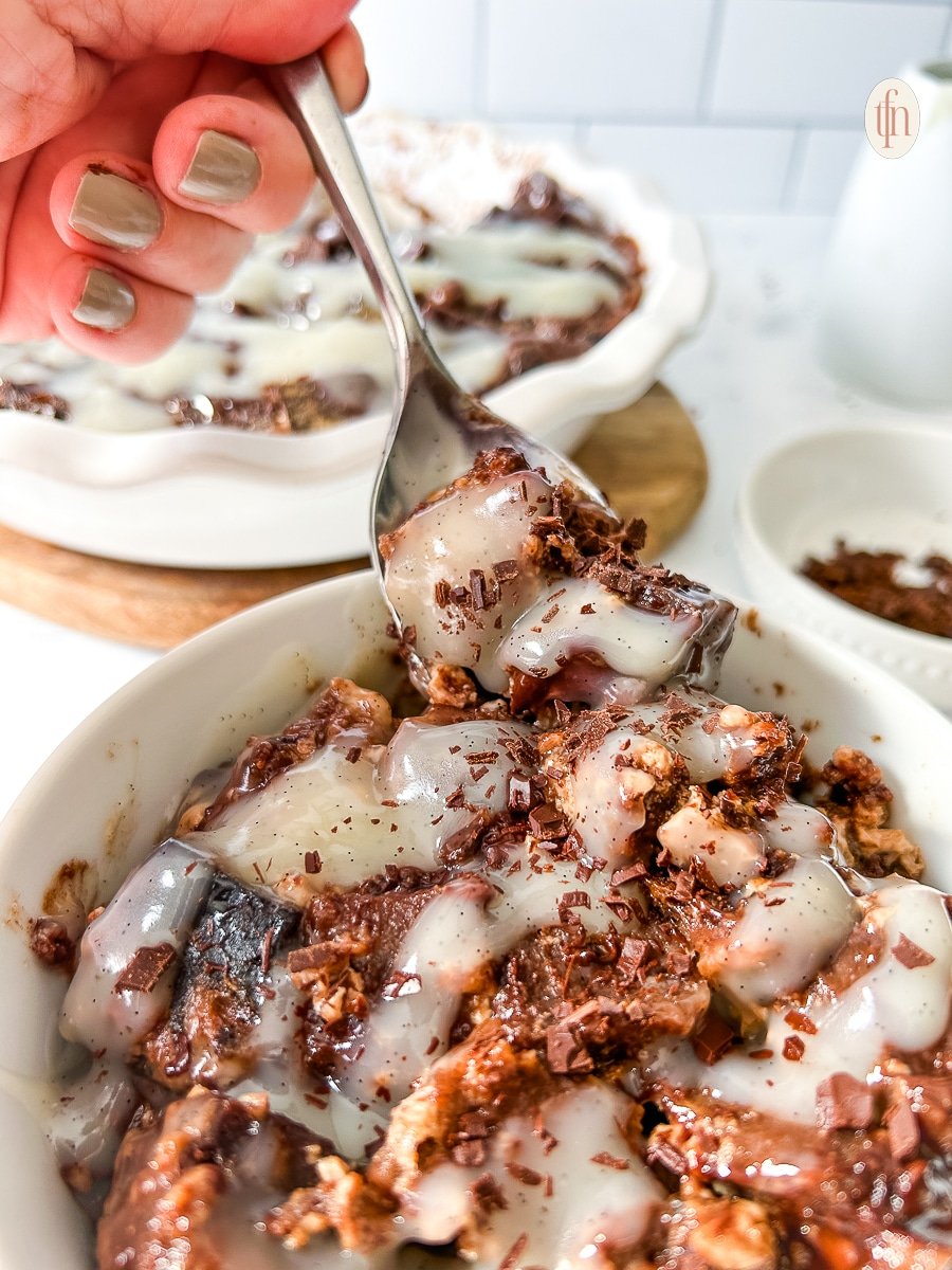 Fork lifting bread pudding from a bowl into the air.