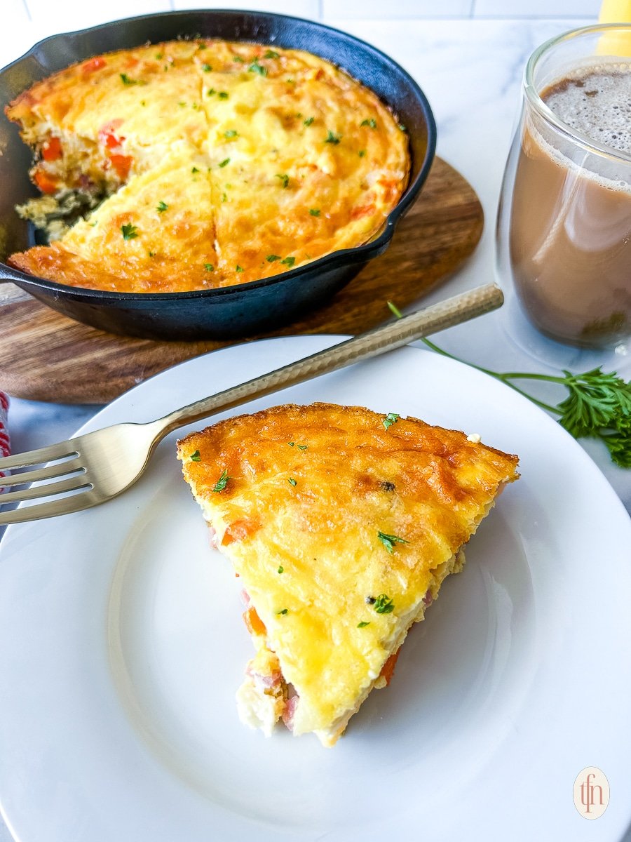 A slice of ham and cheese frittata on a plate.