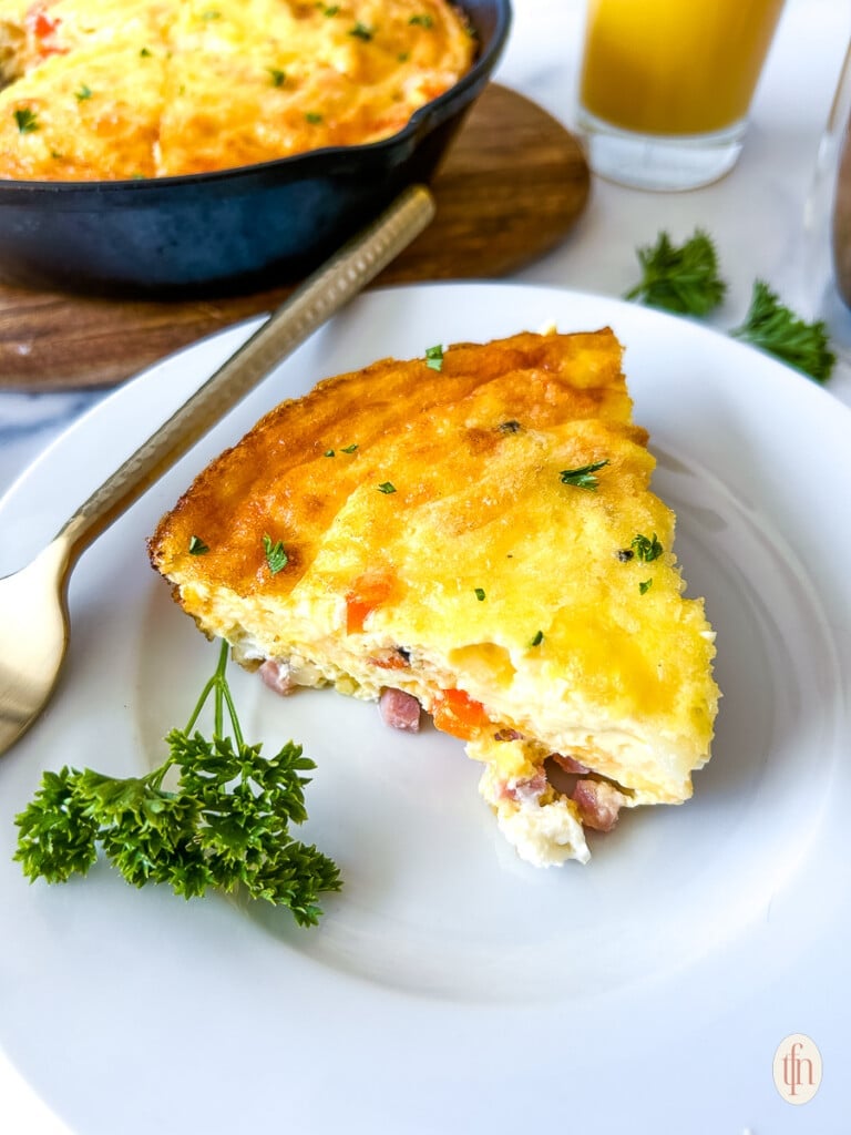 Slice of ham and cheese frittata on a plate.