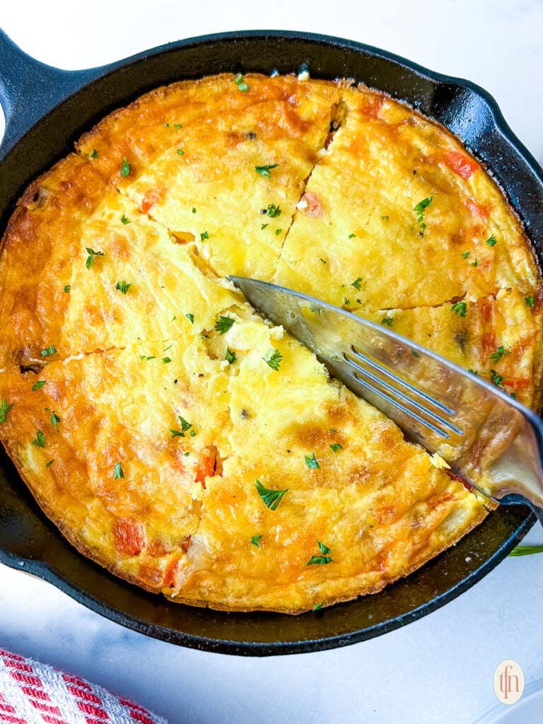 Serving knife slicing into frittata.