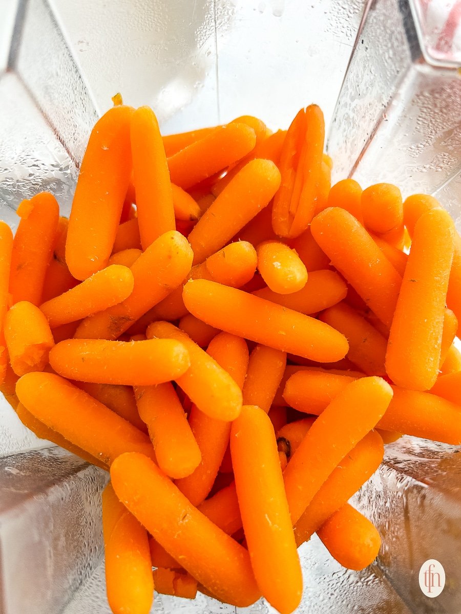 Baby carrots in a blender about to be blended.