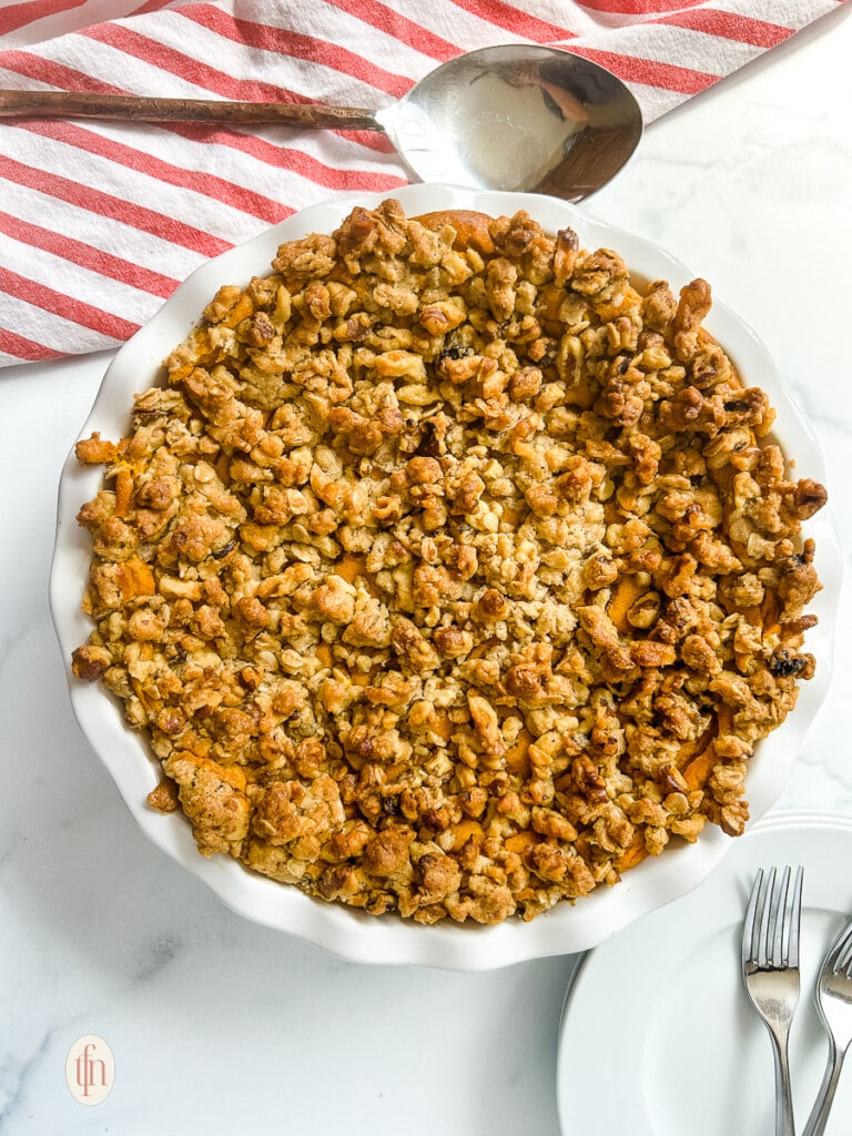 Casserole topped with oats and nuts in a white dish.