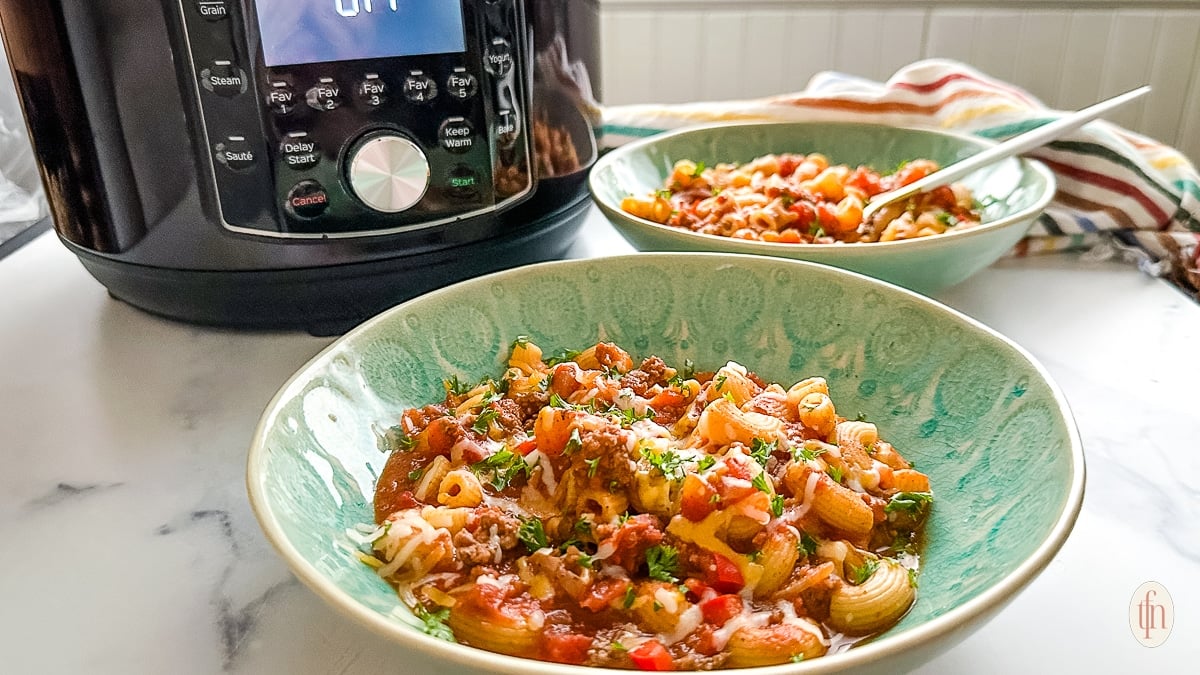 Two servings of chili with macaroni next to an Instant Pot.