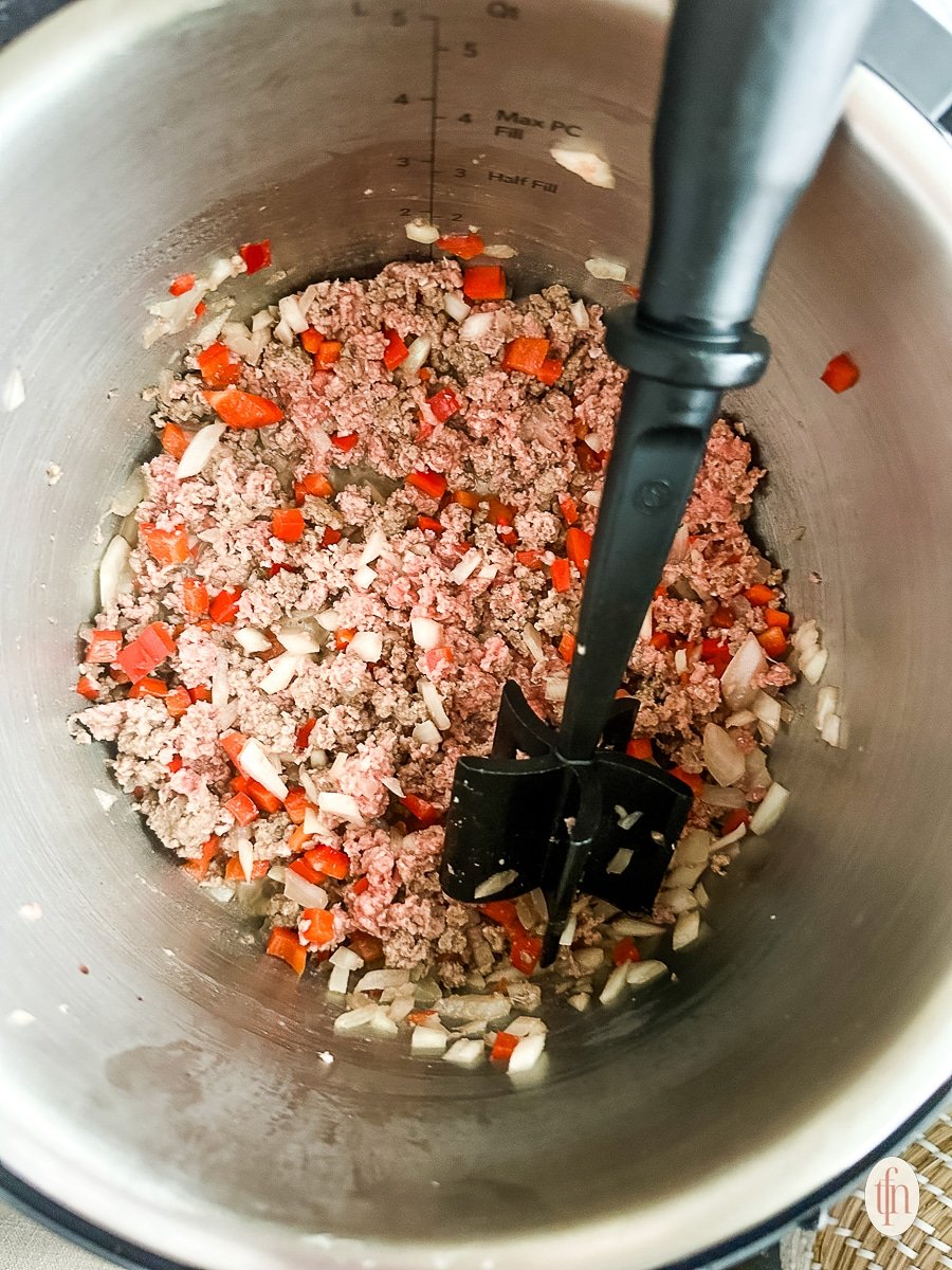 Browning ground beef with diced tomatoes and onion in a large pot.