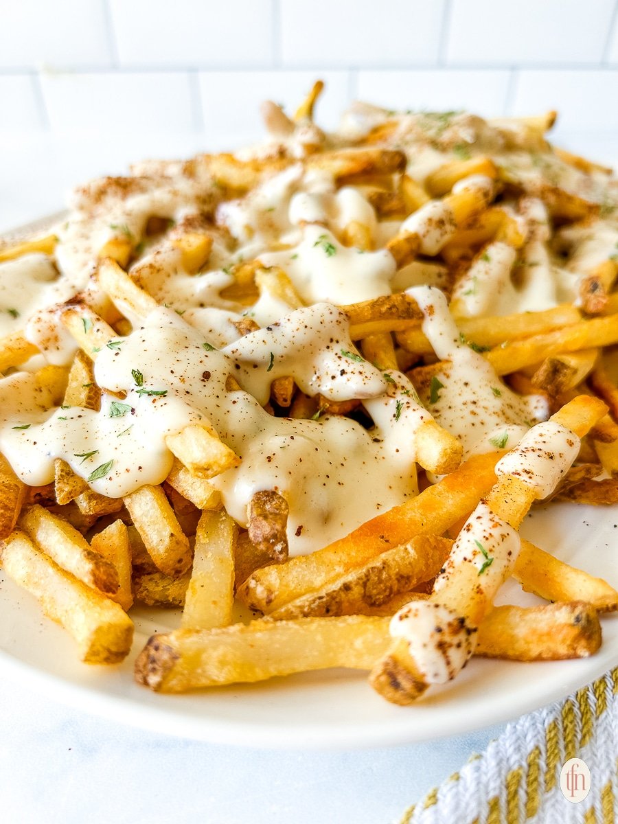 Louisiana Voodoo Fries on a white plate covered with white sauce.