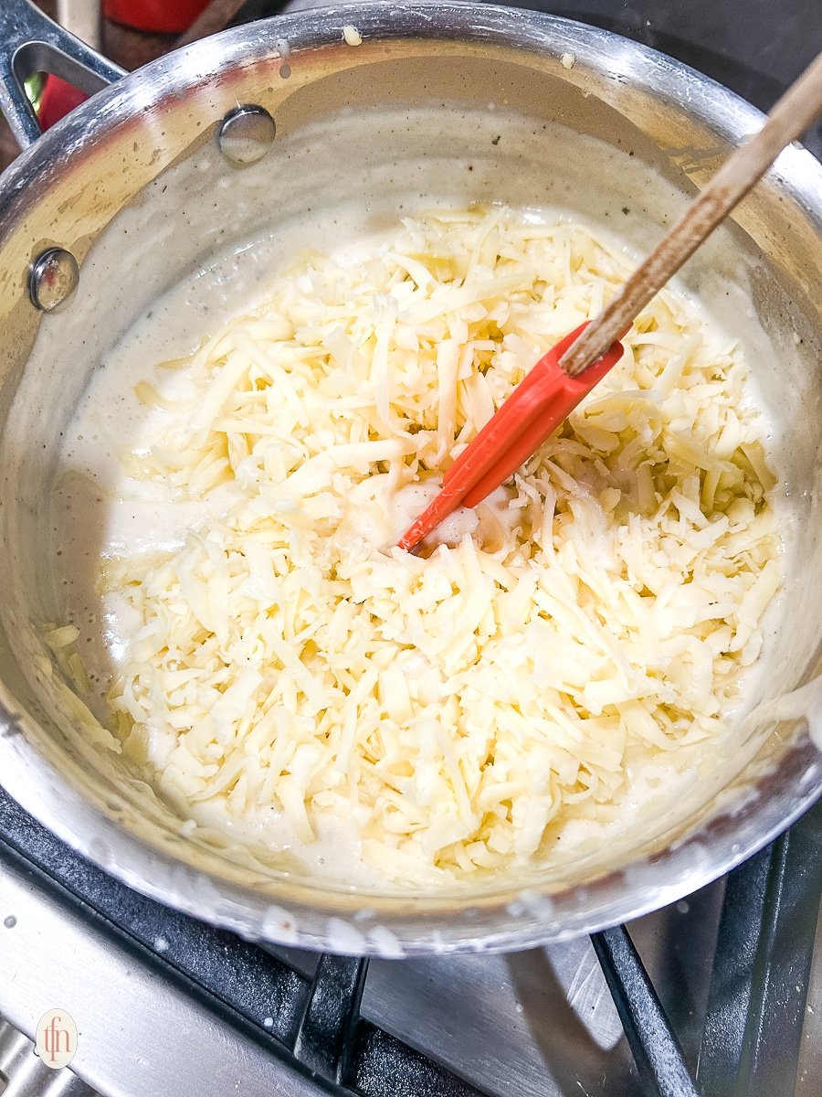 Stirring cheese into the roux with a red spatula.