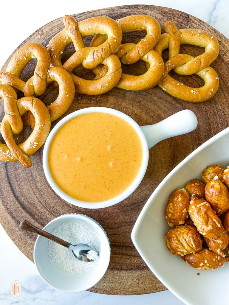 A serving platter with pretzels and pretzel cheese sauce.
