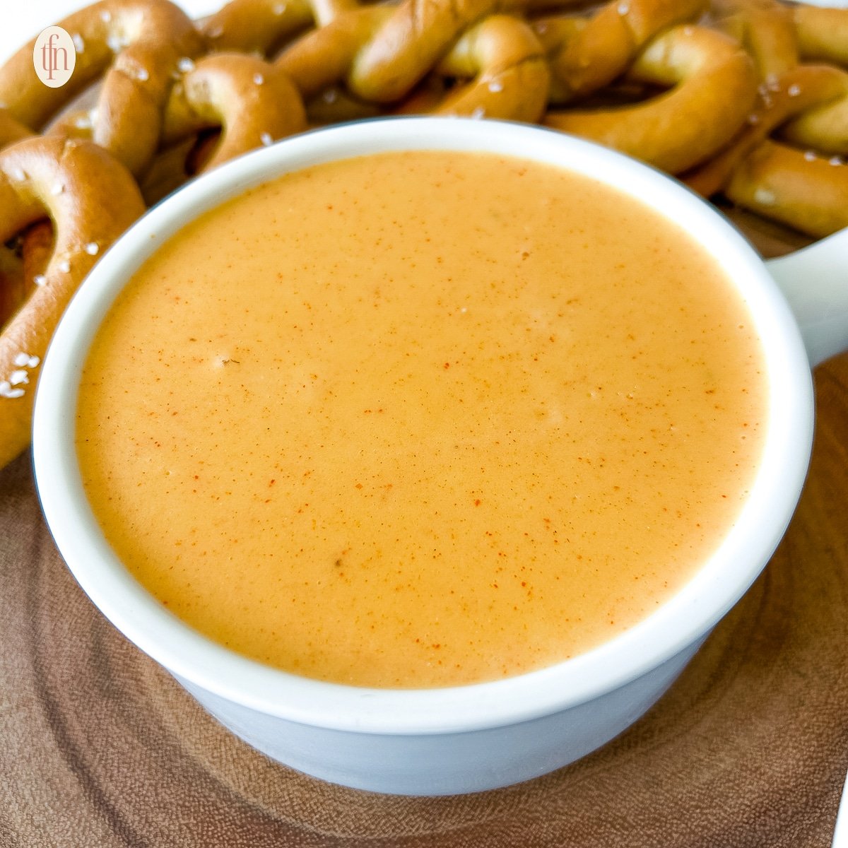 A bowl of Pretzel Cheese Dip with pretzels nearby.