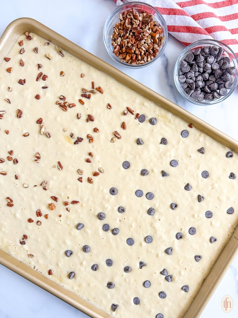 Batter for pancakes in a sheet pan topped with two different kinds of toppings.