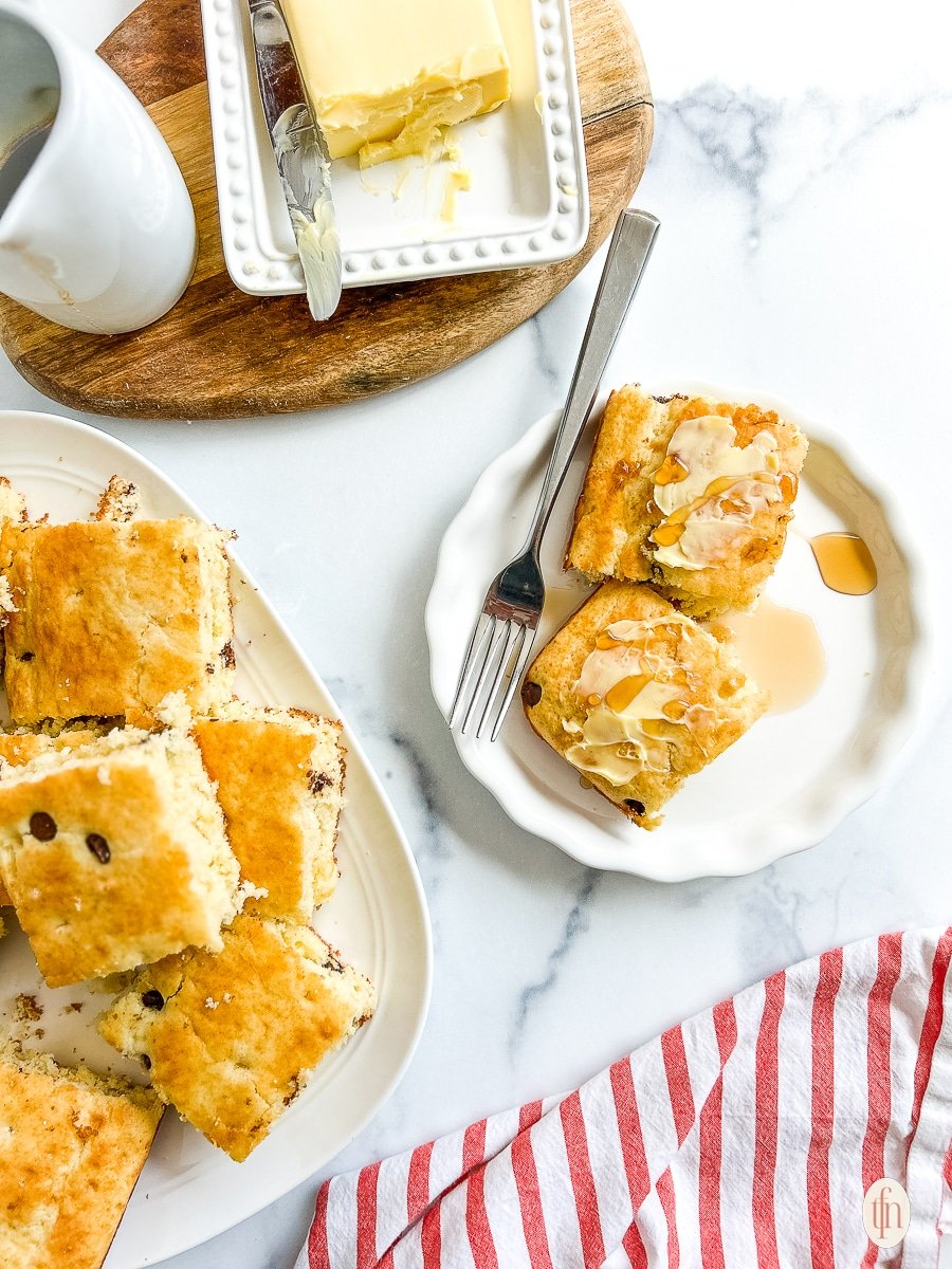 Sheet pan pancakes served on a white plate with syrup over the top.