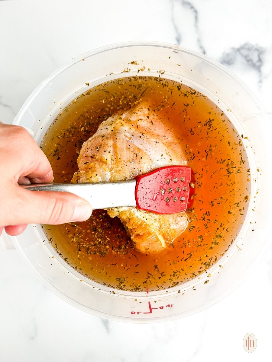 Placing turkey in bucket with brine.