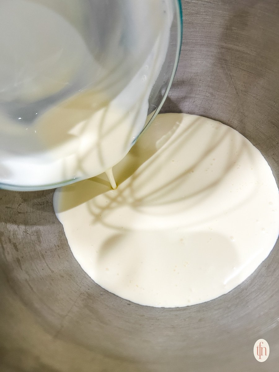 Pouring cream into a stainless steel bowl.