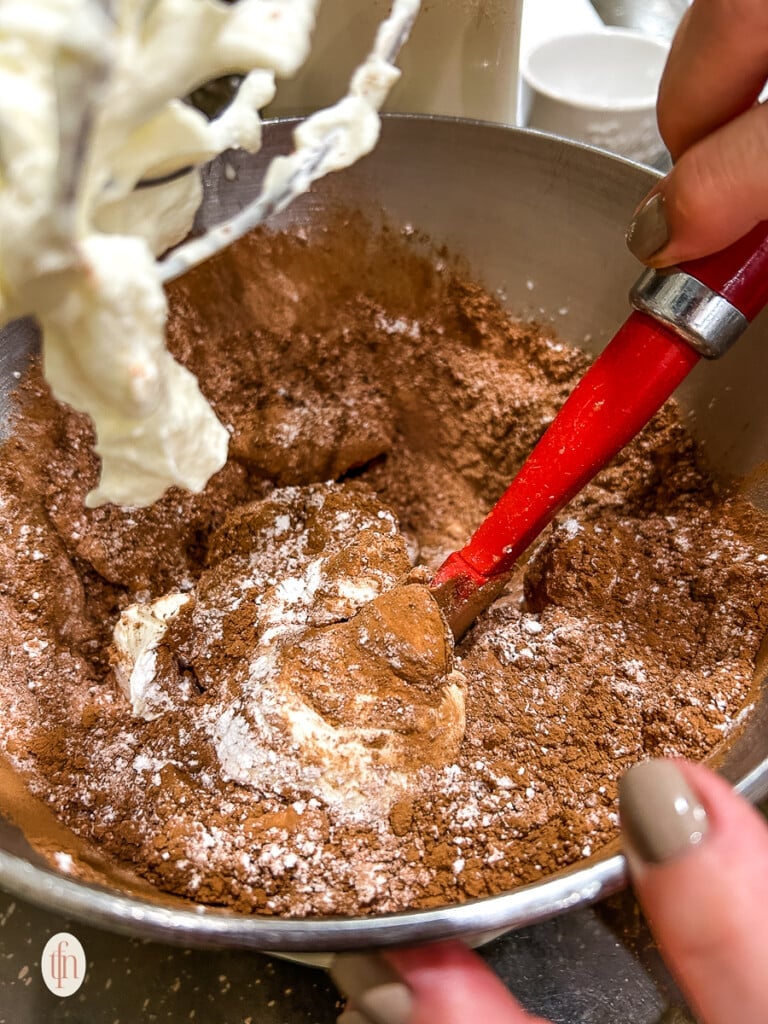 Stirring chocolate and cream in a metal bowl.