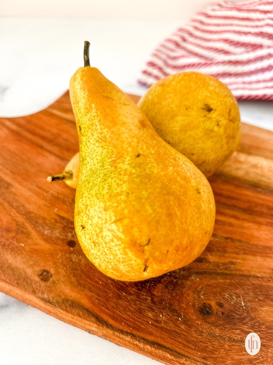 Two ripe pears sitting on a cutting board.