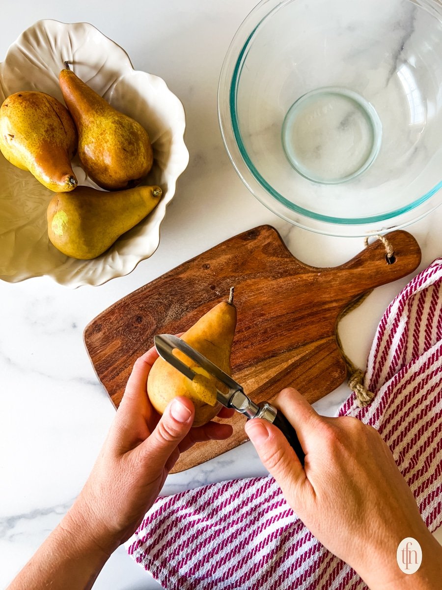 Peeling a pear with a vegetable peeler.