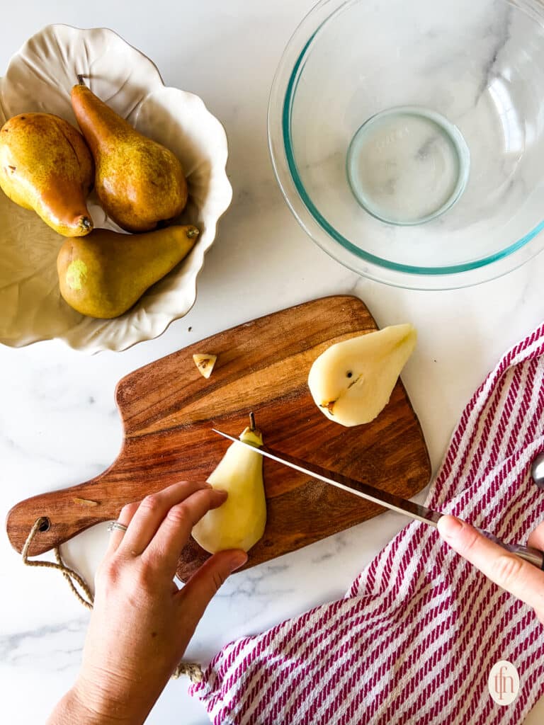 Slicing off the stem end of a pear with a knife.