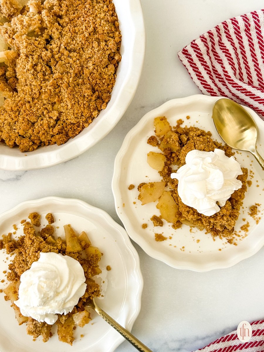 Two plates of pear crumble on a white background.