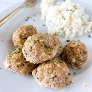 Turkey zucchini meatballs on a white plate next to a fork.