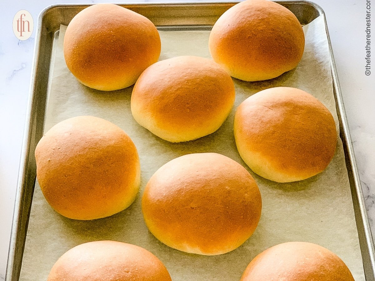 Homemade burger buns on a baking sheet.